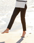 Person wearing a black and white striped sweater and dark pants on a sandy beach.