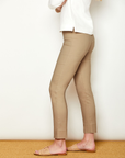 Person wearing beige pants and a white top against a plain background