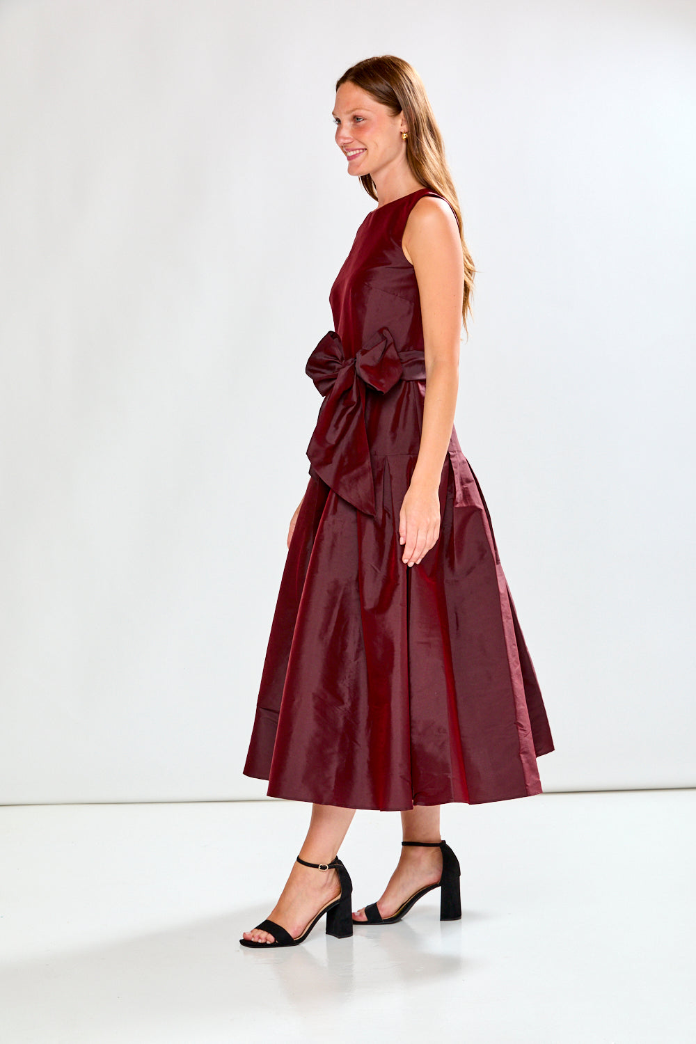 Woman wearing a burgundy dress with a bow detail on a white background
