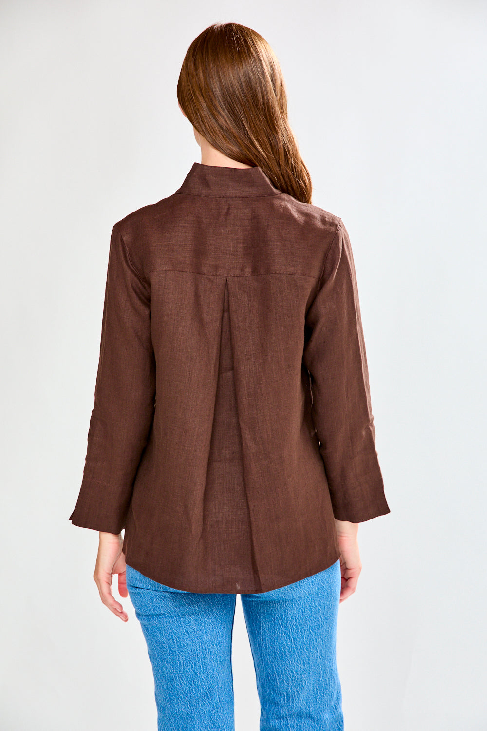 Person wearing a brown jacket and blue jeans on a white background