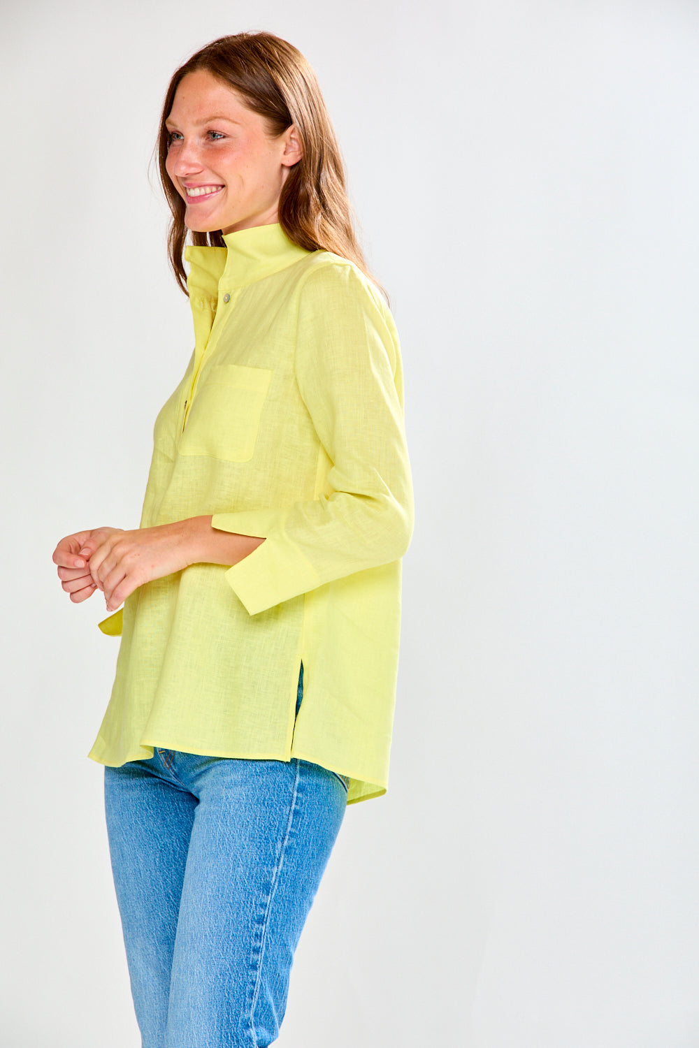 Woman wearing a sunflower and blue jeans against a white background