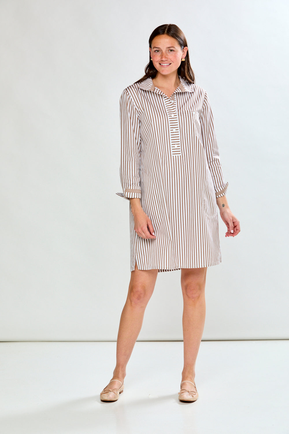 Woman wearing a striped shirt dress against a white background