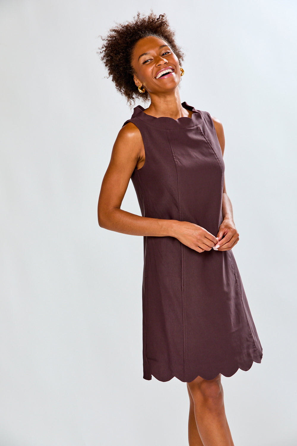 Woman wearing a sleeveless brown dress against a white background