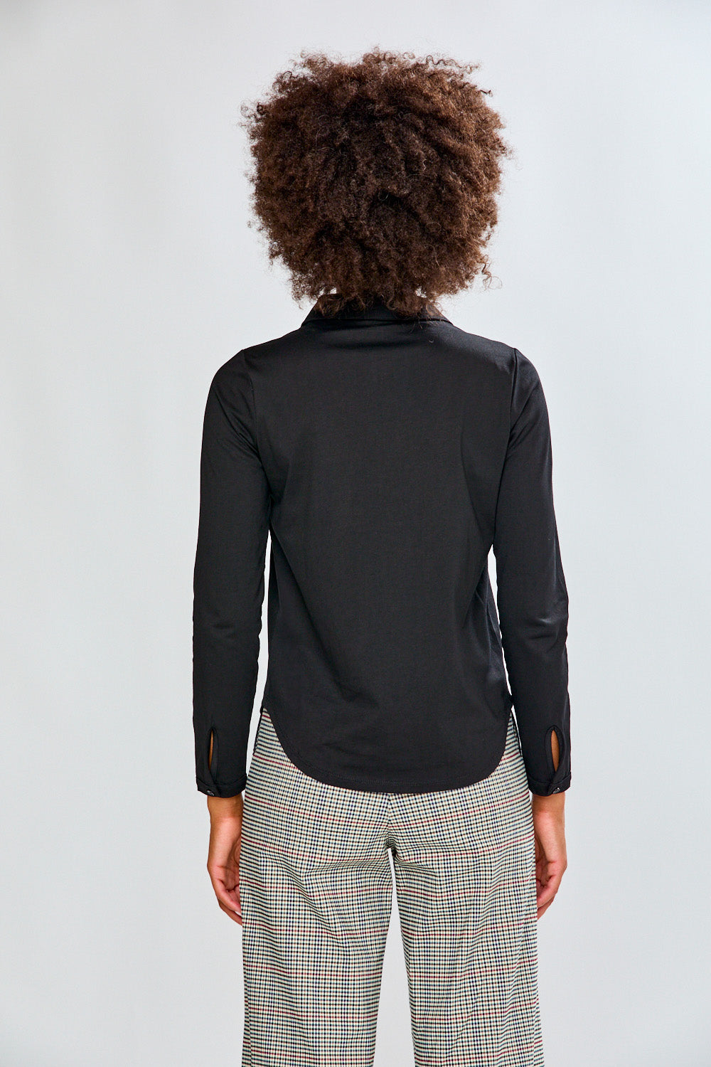 Woman wearing a black shirt and plaid pants on a white background
