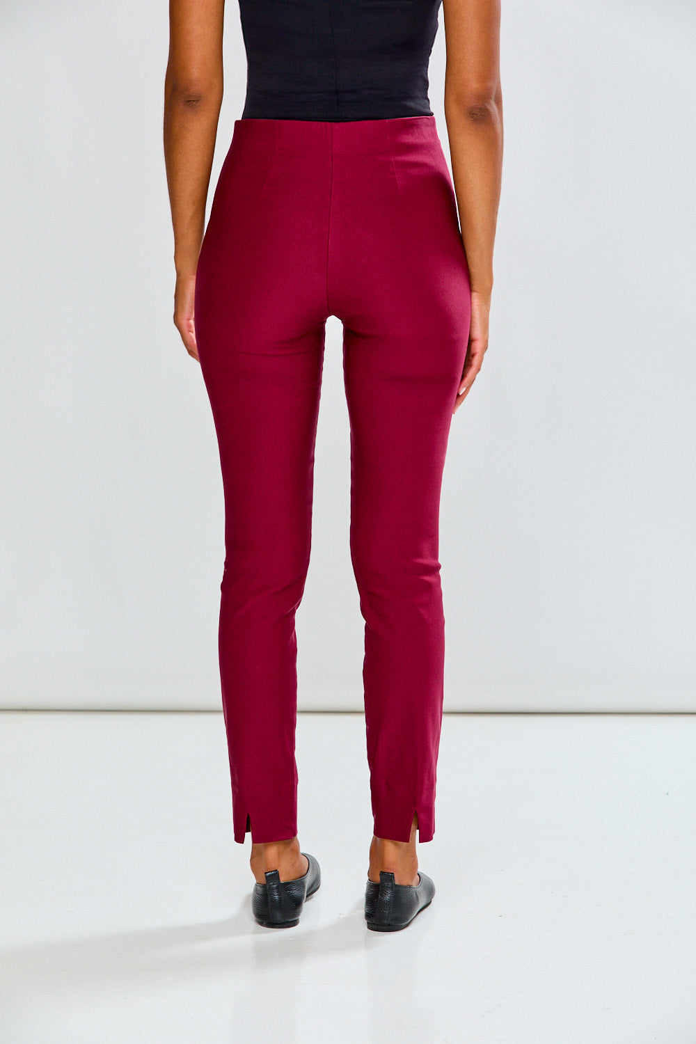 Person wearing raisin pants and black shoes on a white background