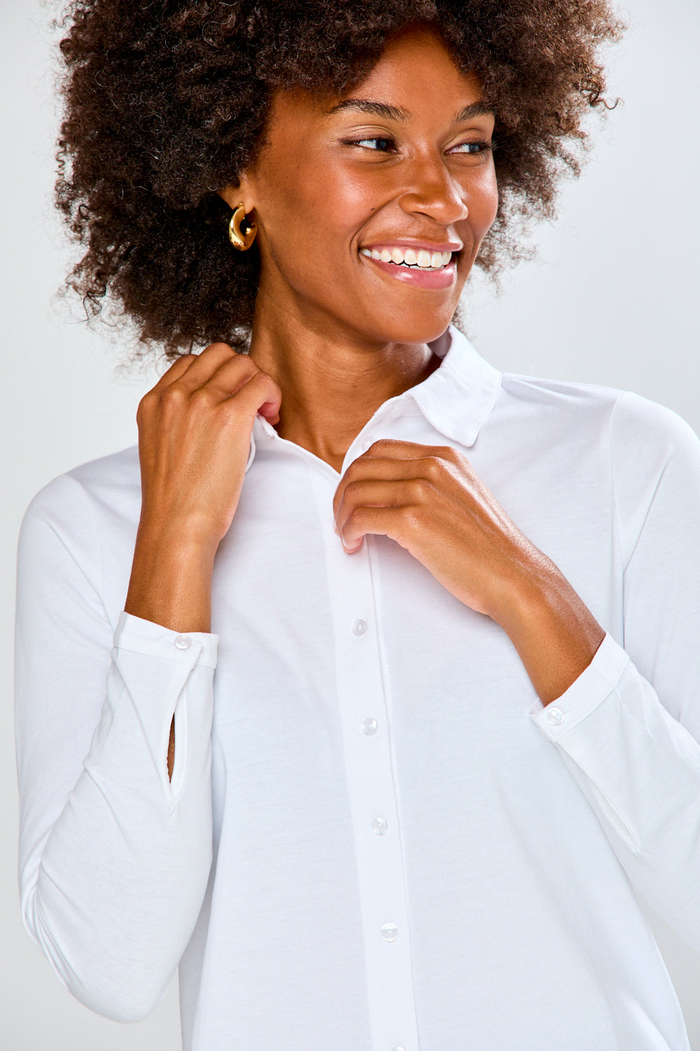 Woman wearing a white shirt and green pants against a plain background