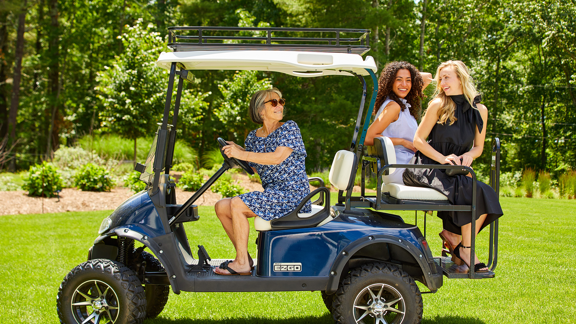 Sara Campbell driving a gold cart with two women in the back