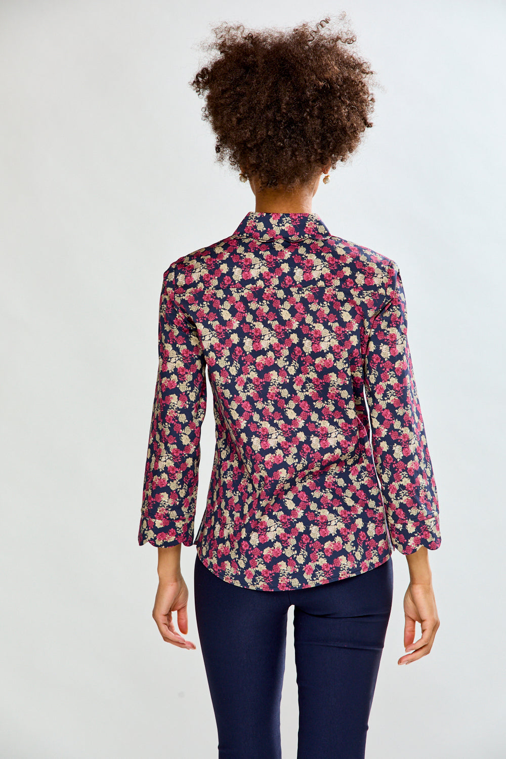 Woman wearing a floral shirt and dark pants on a white background
