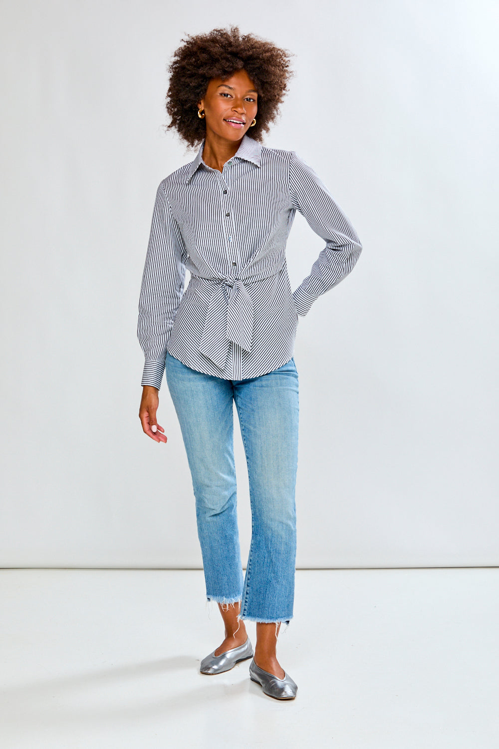 Woman wearing a striped shirt and jeans on a plain background