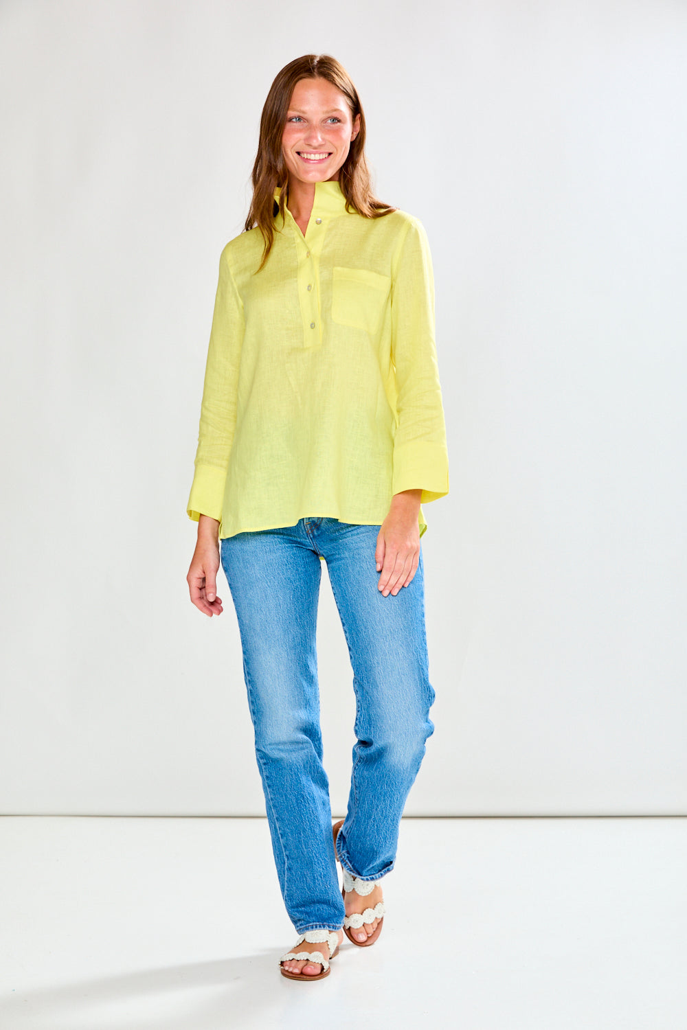 Woman wearing a sunflower and blue jeans against a white background