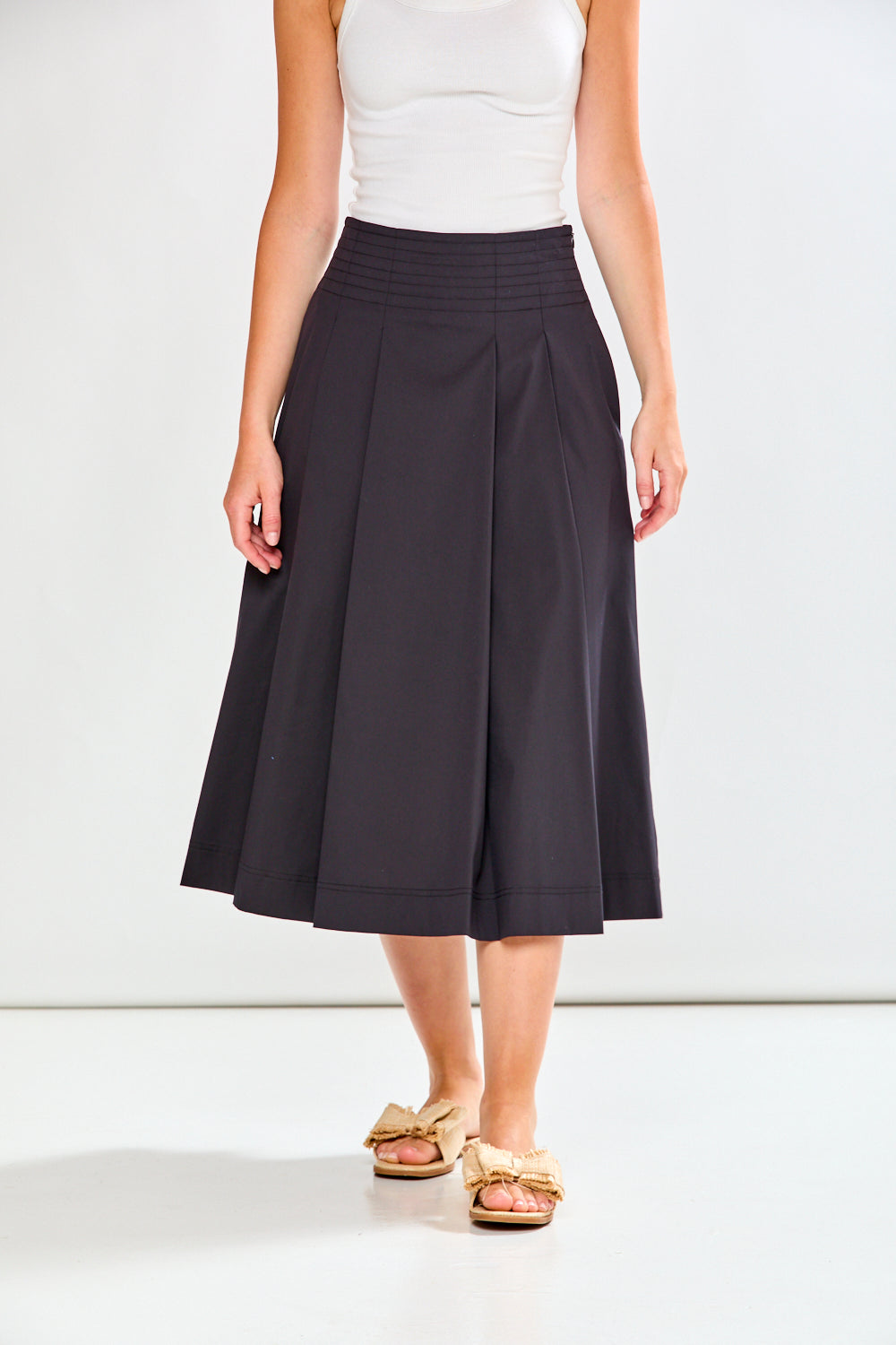 Person wearing a black skirt and white top on a white background