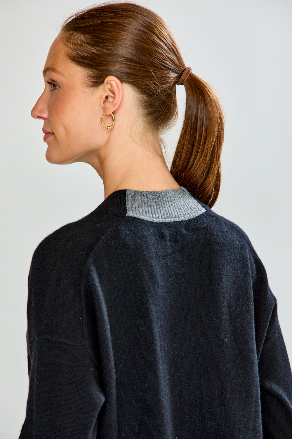 Woman wearing a black sweater and blue jeans against a plain background