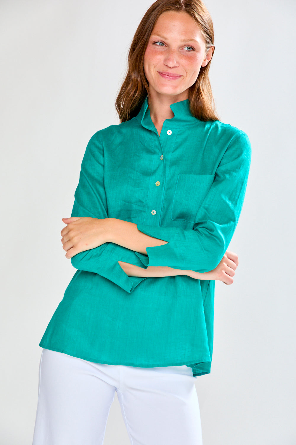 Woman wearing a teal shirt with long sleeves on a white background