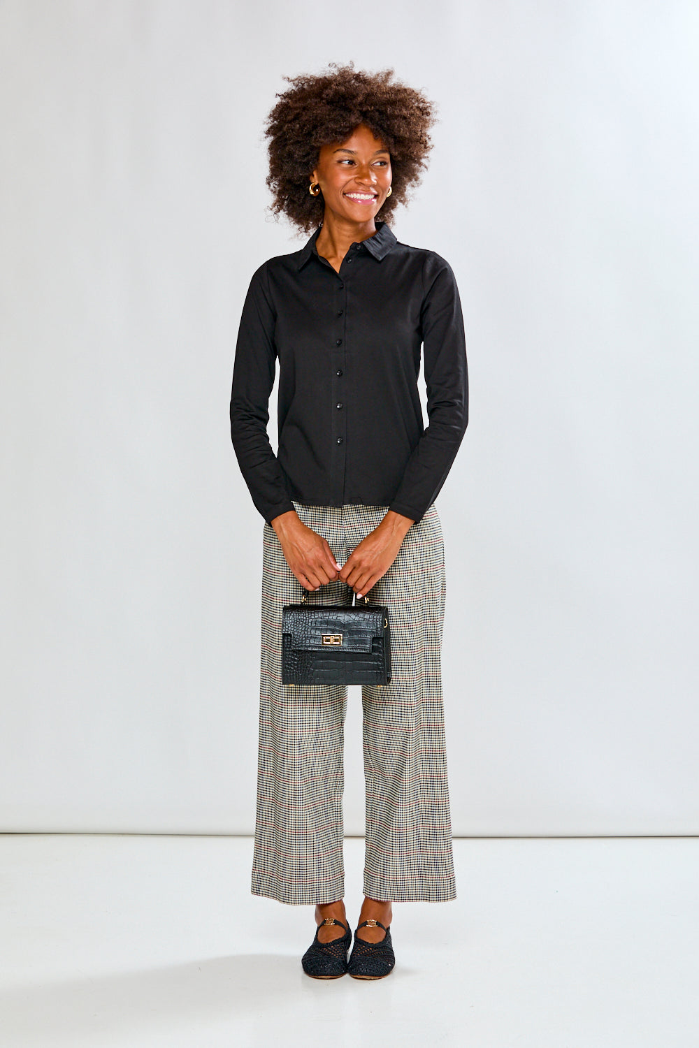 Woman wearing a black shirt and plaid pants on a white background