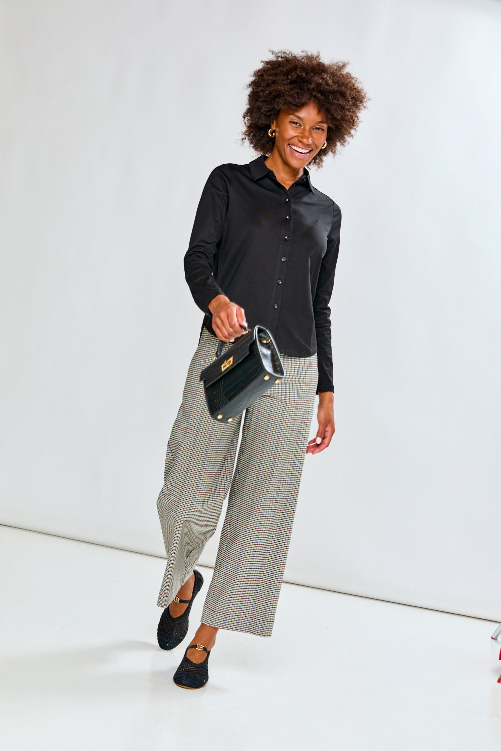 Woman wearing a black shirt and plaid pants on a white background