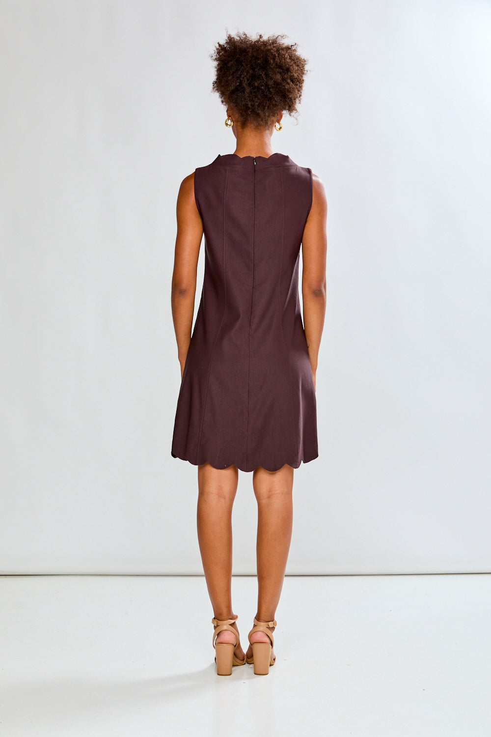 Person wearing a sleeveless brown dress on a white background