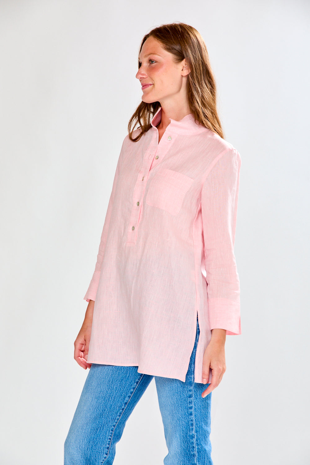Woman wearing a light pink shirt and blue jeans on a white background