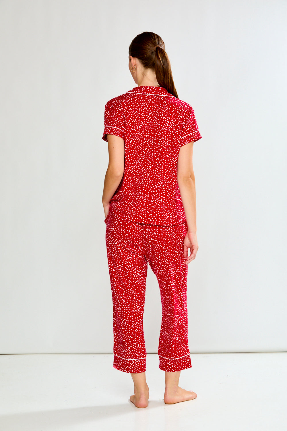 Woman wearing a red patterned pajama set on a white background