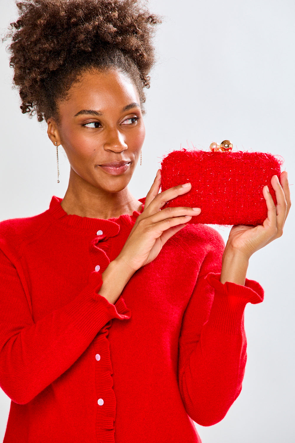 Woman holding a red clutch against a white background