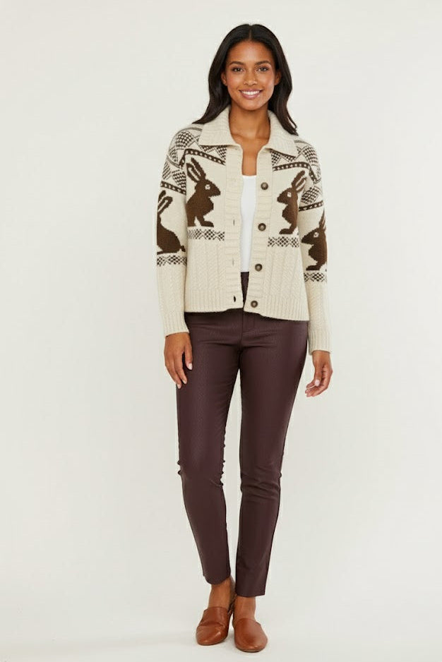 Woman wearing a patterned cardigan with brown pants on a white background