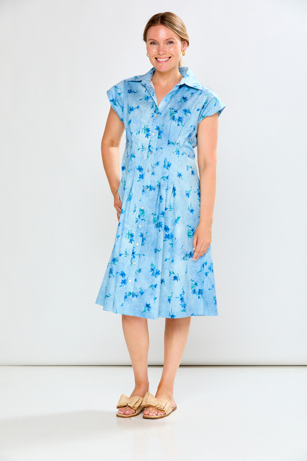 Woman wearing a blue floral dress against a white background