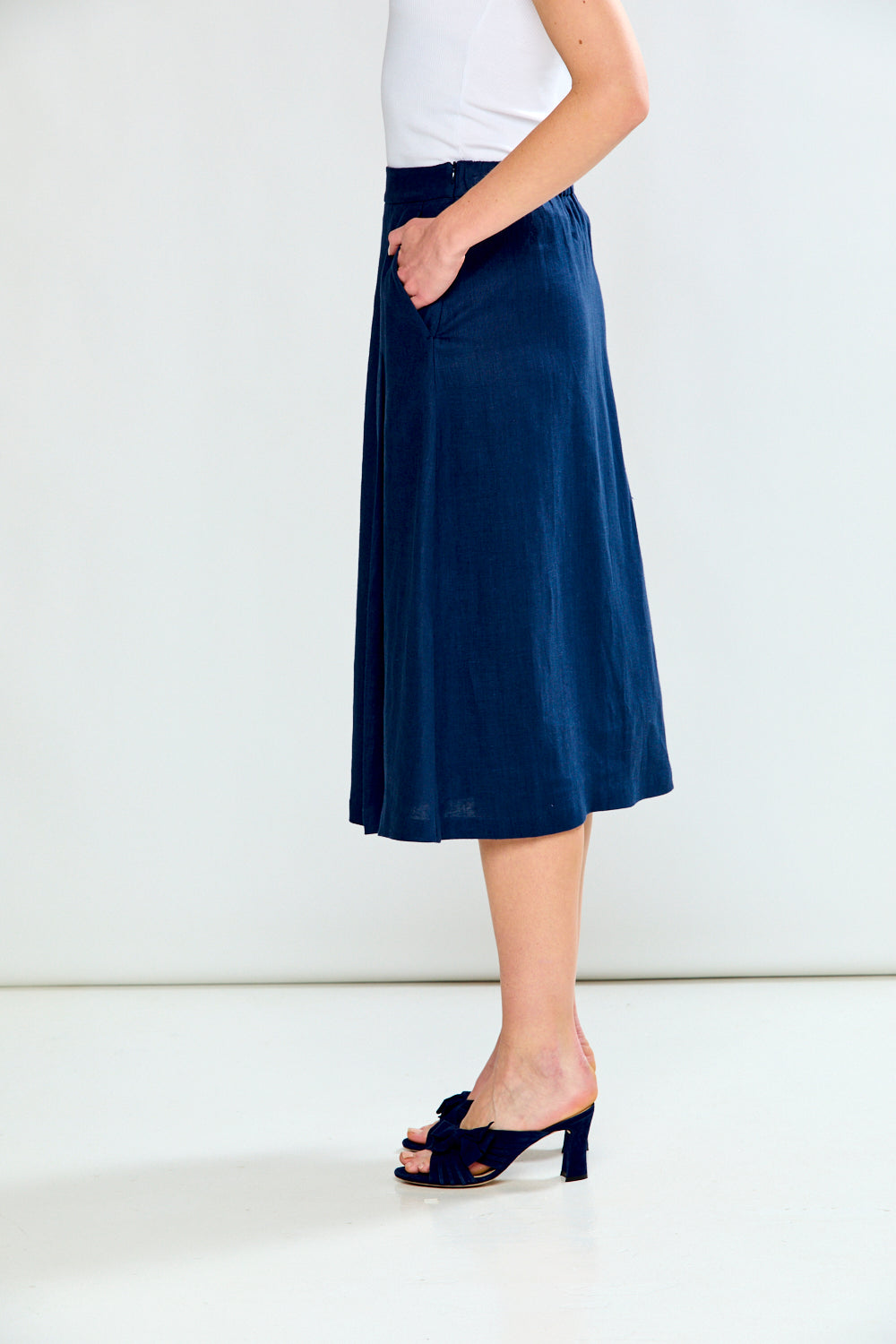 Person wearing a navy blue skirt and black shoes on a white background