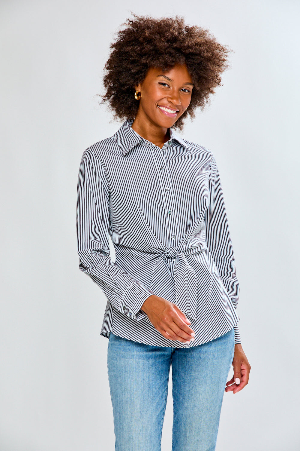 Woman wearing a striped shirt and jeans on a plain background