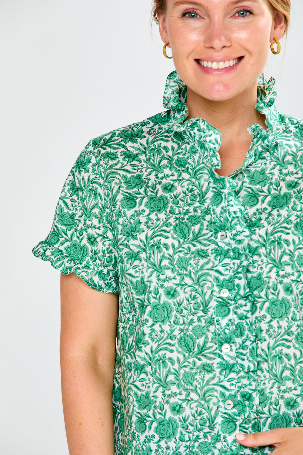 Woman wearing a green floral blouse against a white background