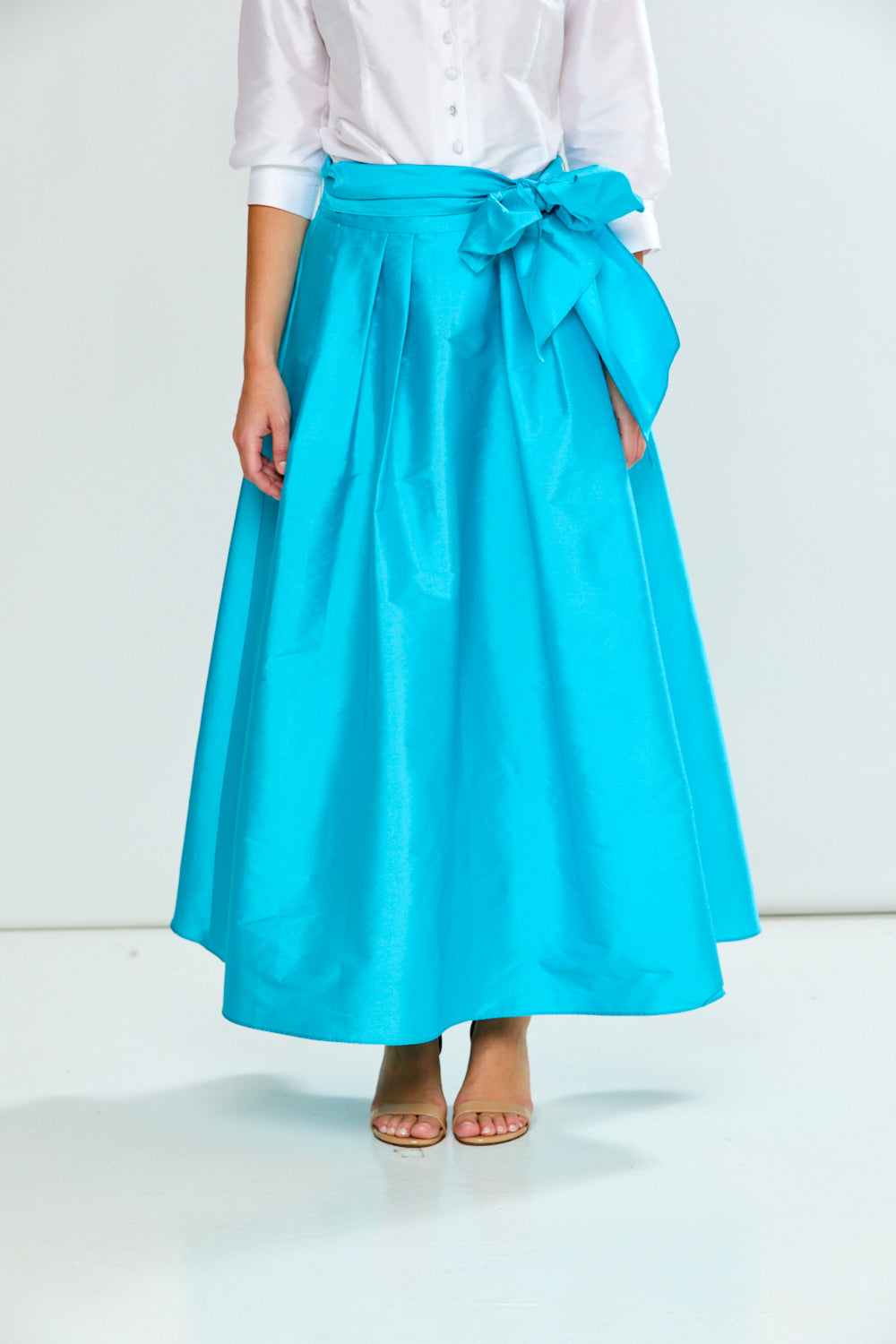 Person wearing a light blue skirt with a white shirt on a white background