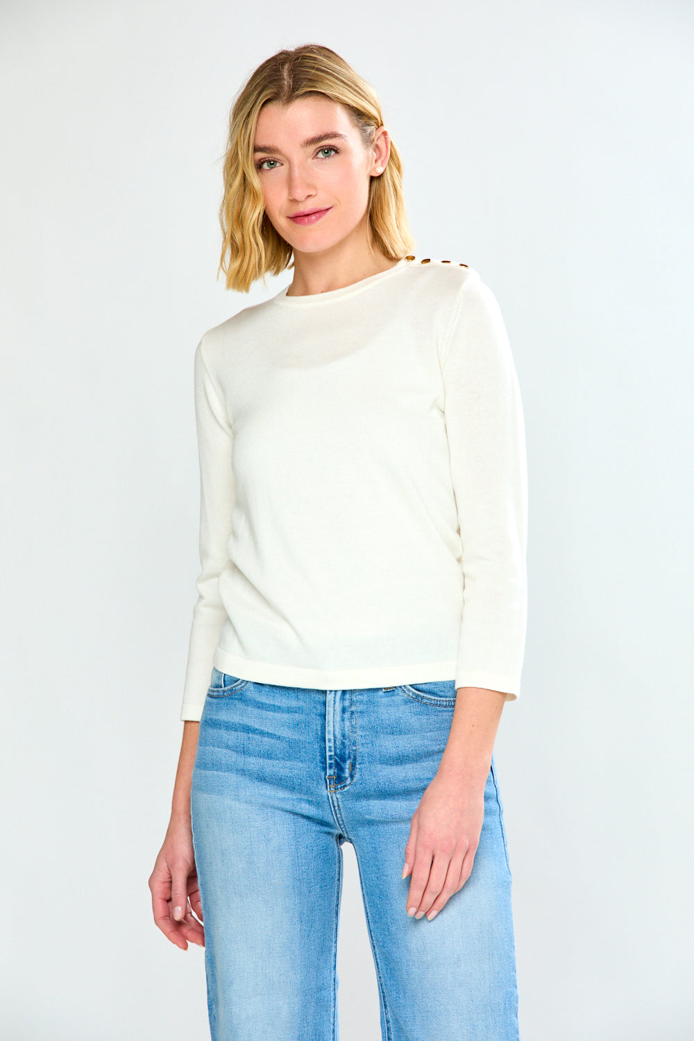 Woman wearing a white sweater and light blue jeans on a white background
