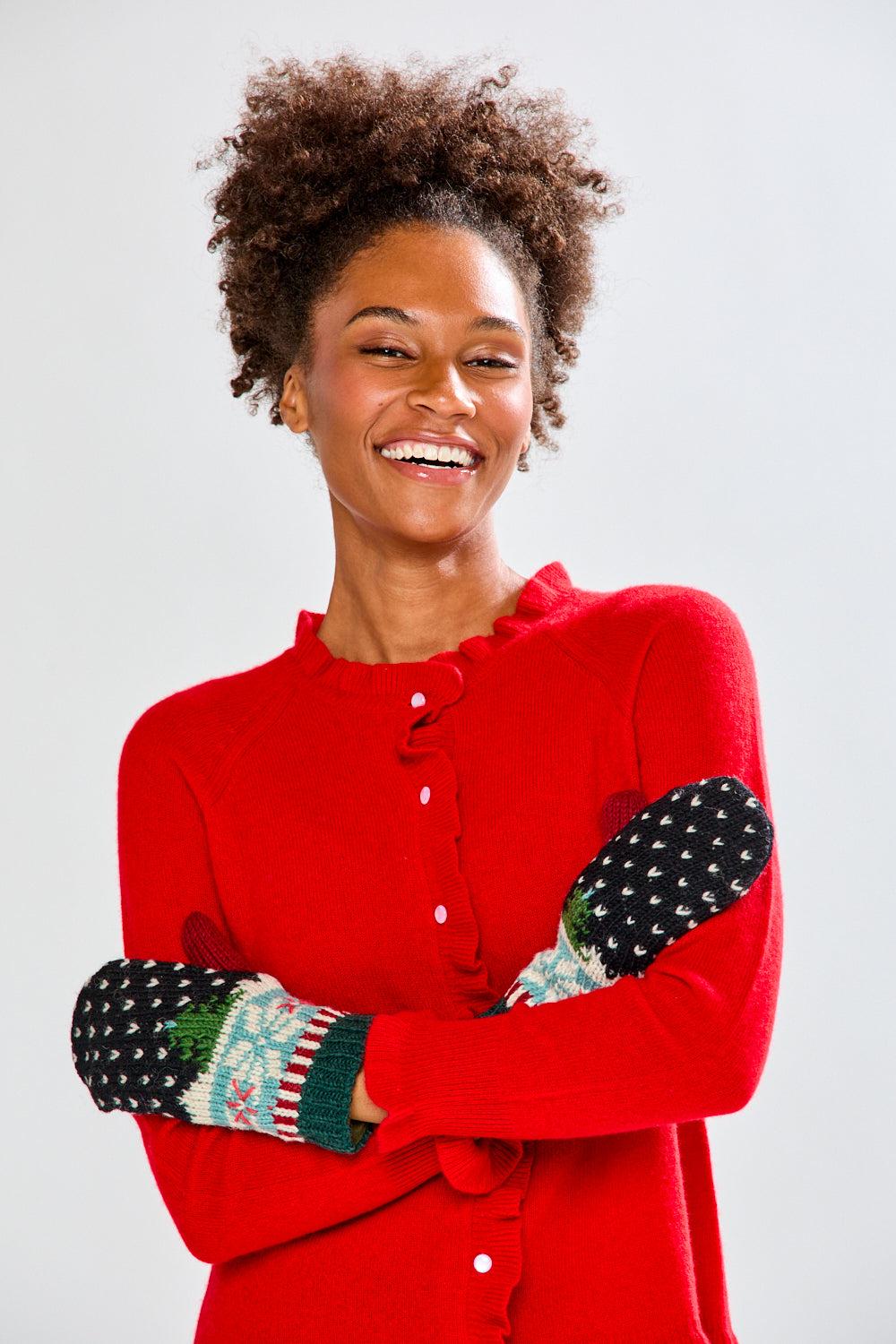 Woman wearing a red sweater and festive mittens on a plain background