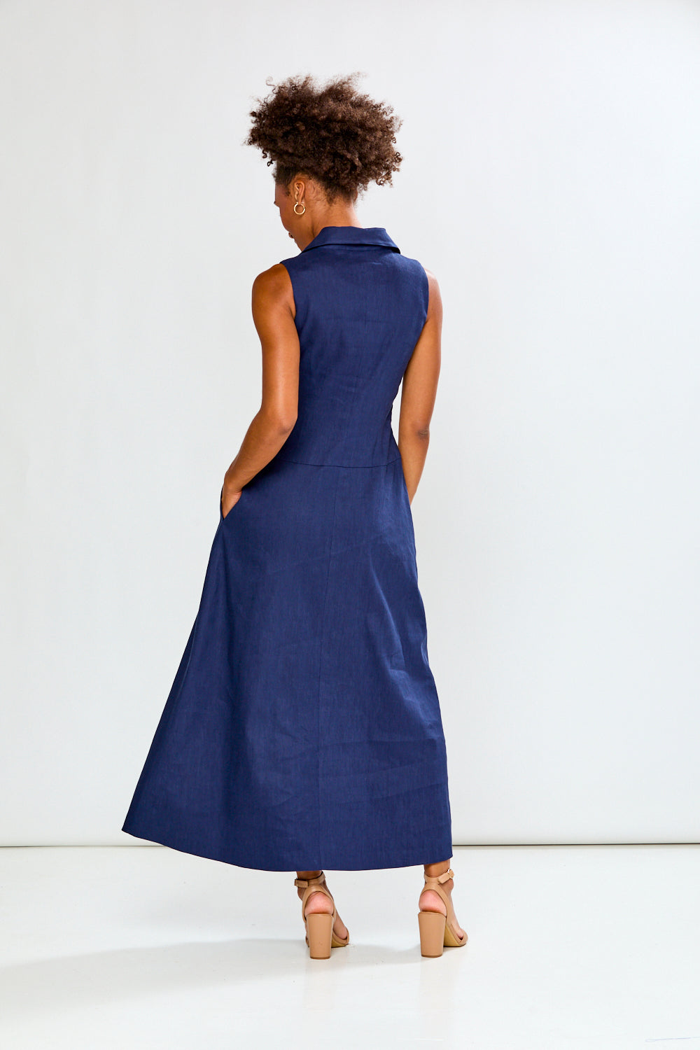 Woman wearing a blue sleeveless dress against a white background