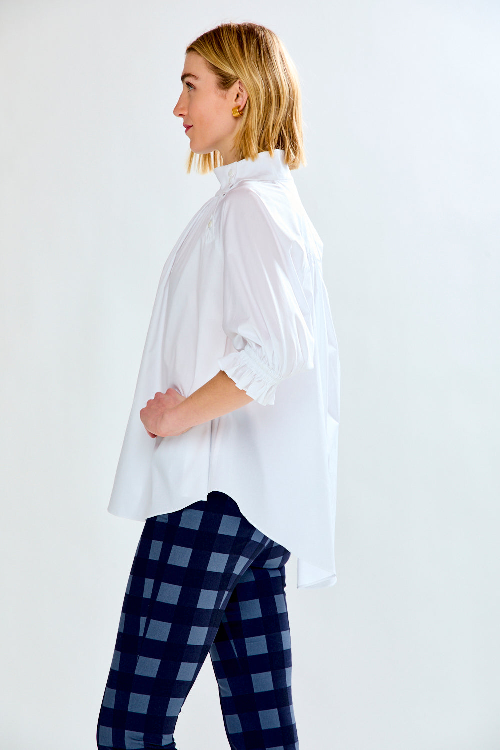 Person wearing a white shirt and blue plaid pants on a white background