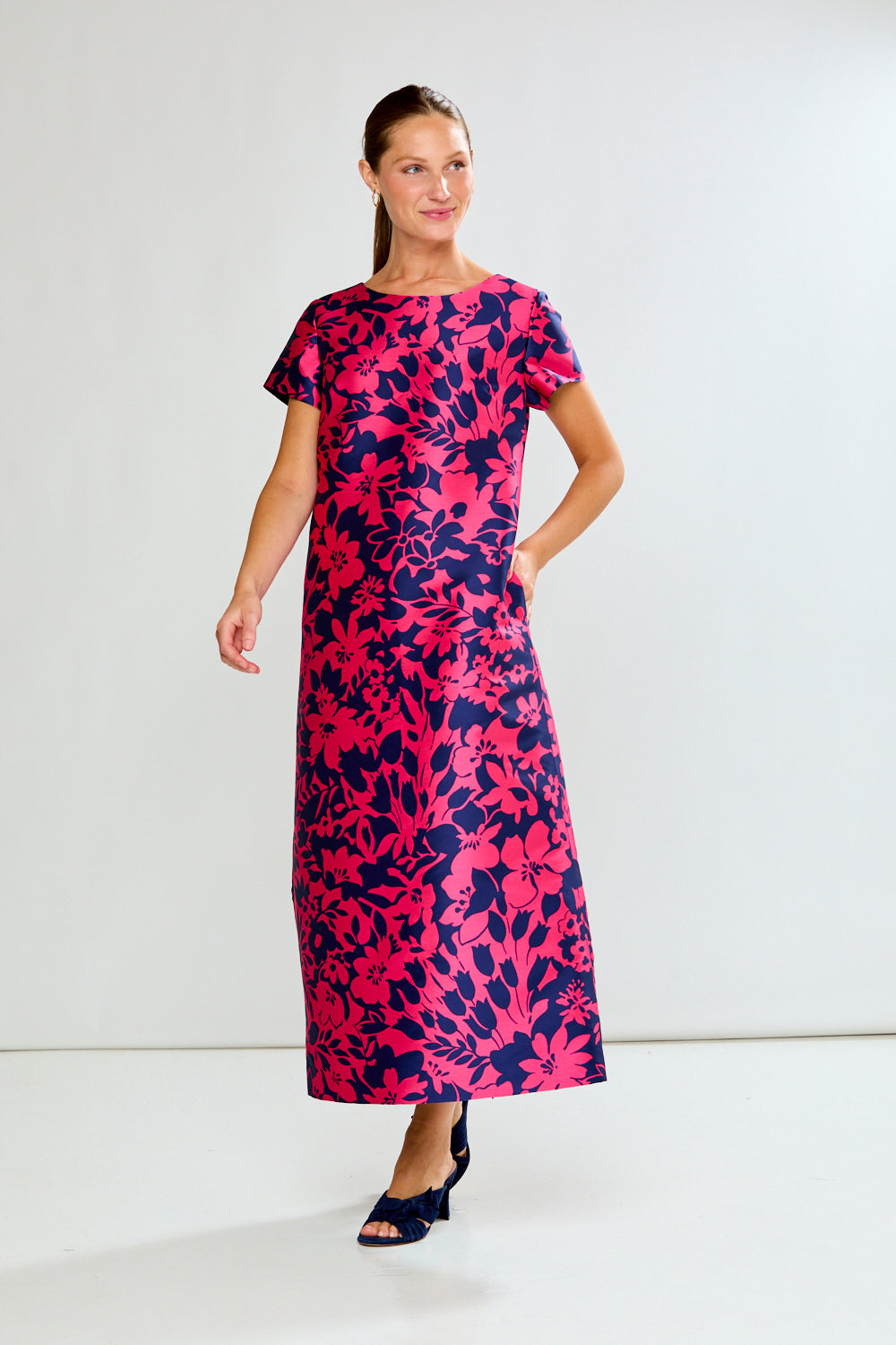 Woman wearing a pink and navy floral dress on a white background