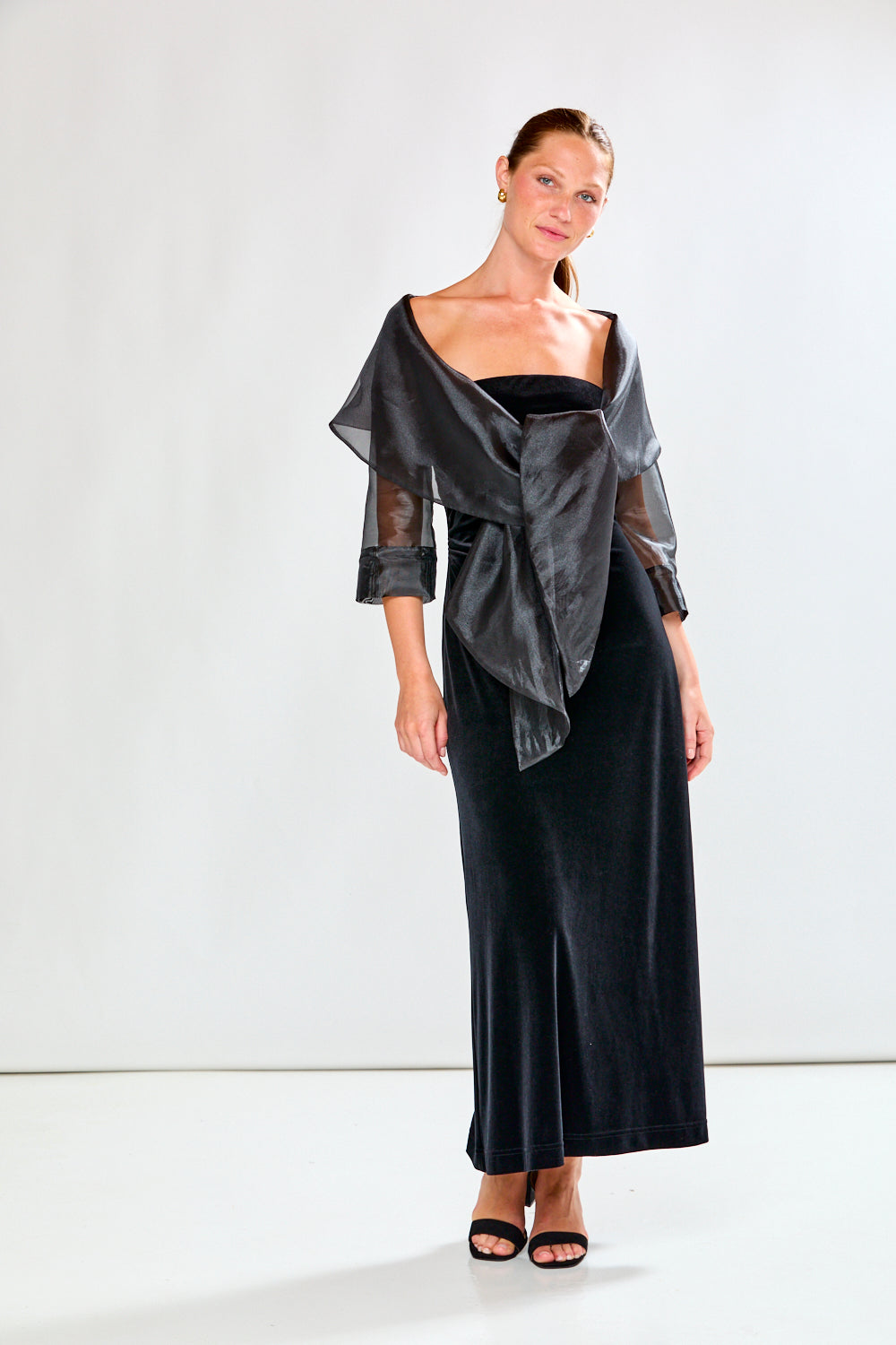 Woman wearing a black dress and black shawl against a white background