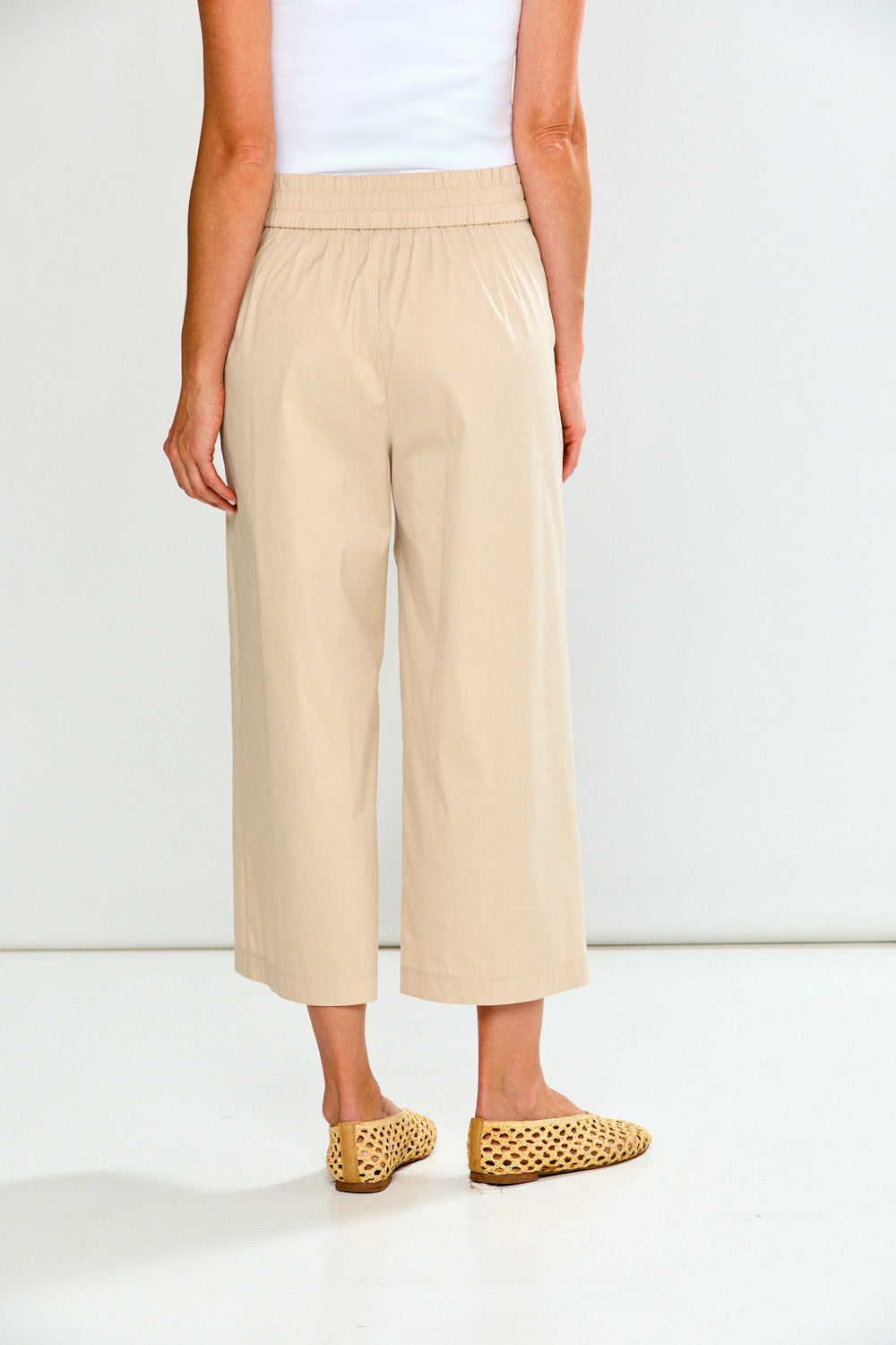 Woman wearing sand wide-leg pants on a white background