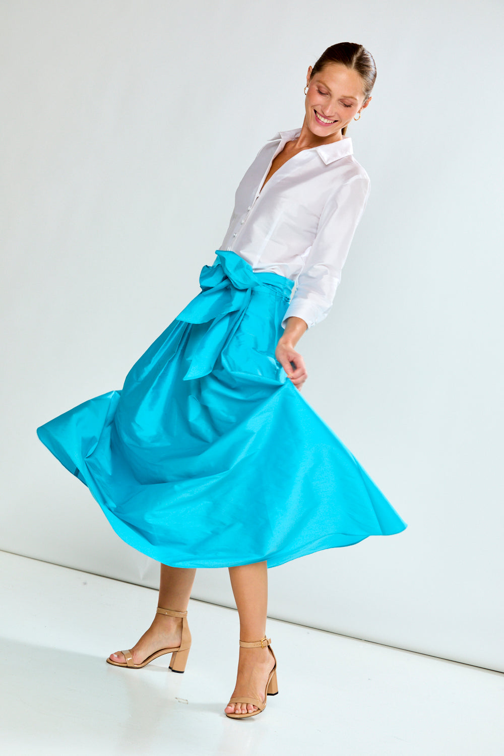 Woman wearing a white blouse and blue skirt on a white background