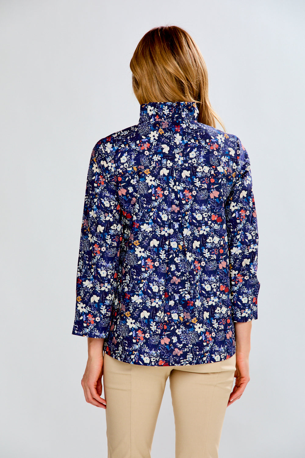 Woman wearing a floral patterned shirt on a plain background