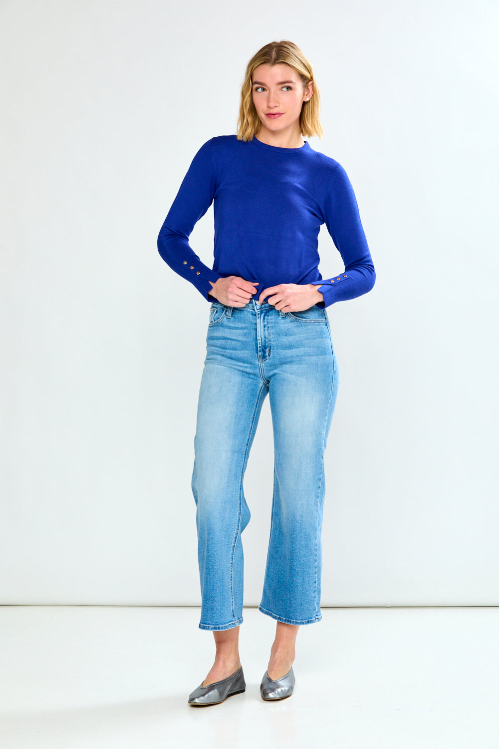 Woman wearing a blue sweater and light blue jeans on a white background