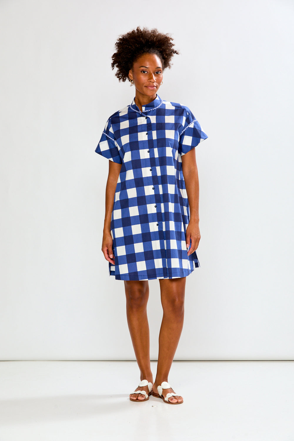 Woman wearing a blue and white checkered dress against a white background