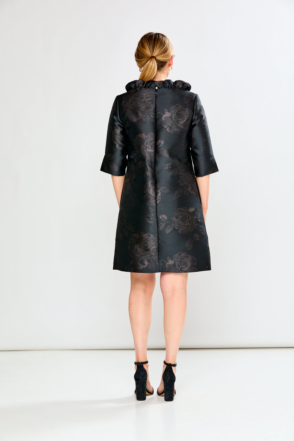 Woman wearing a black floral coat against a white background