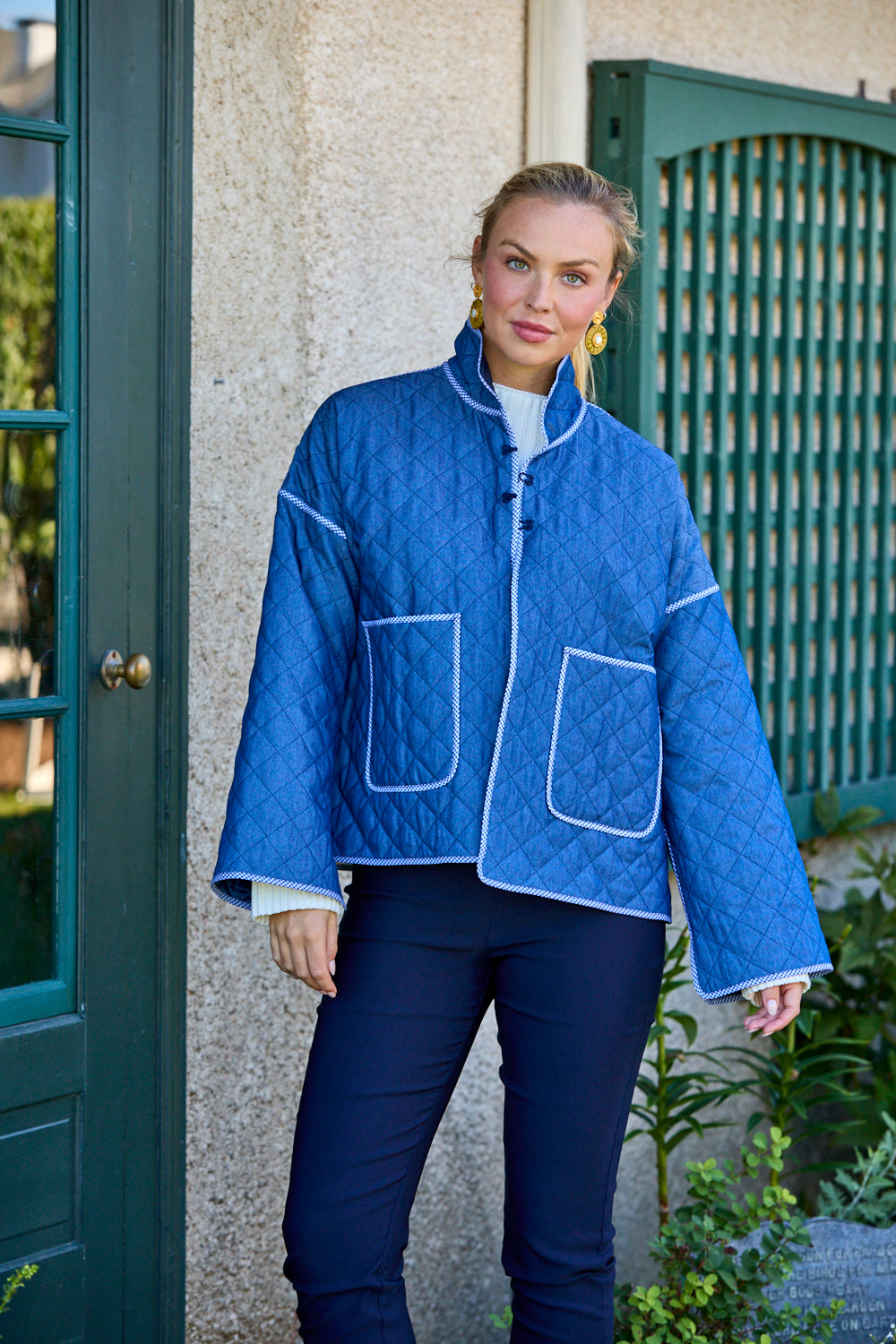 Woman wearing a blue quilted jacket standing outside a building.