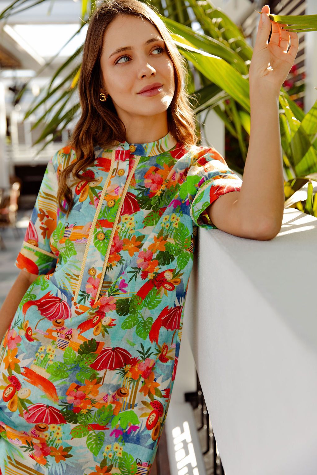 Woman wearing a colorful floral dress with a tropical pattern, standing outdoors.