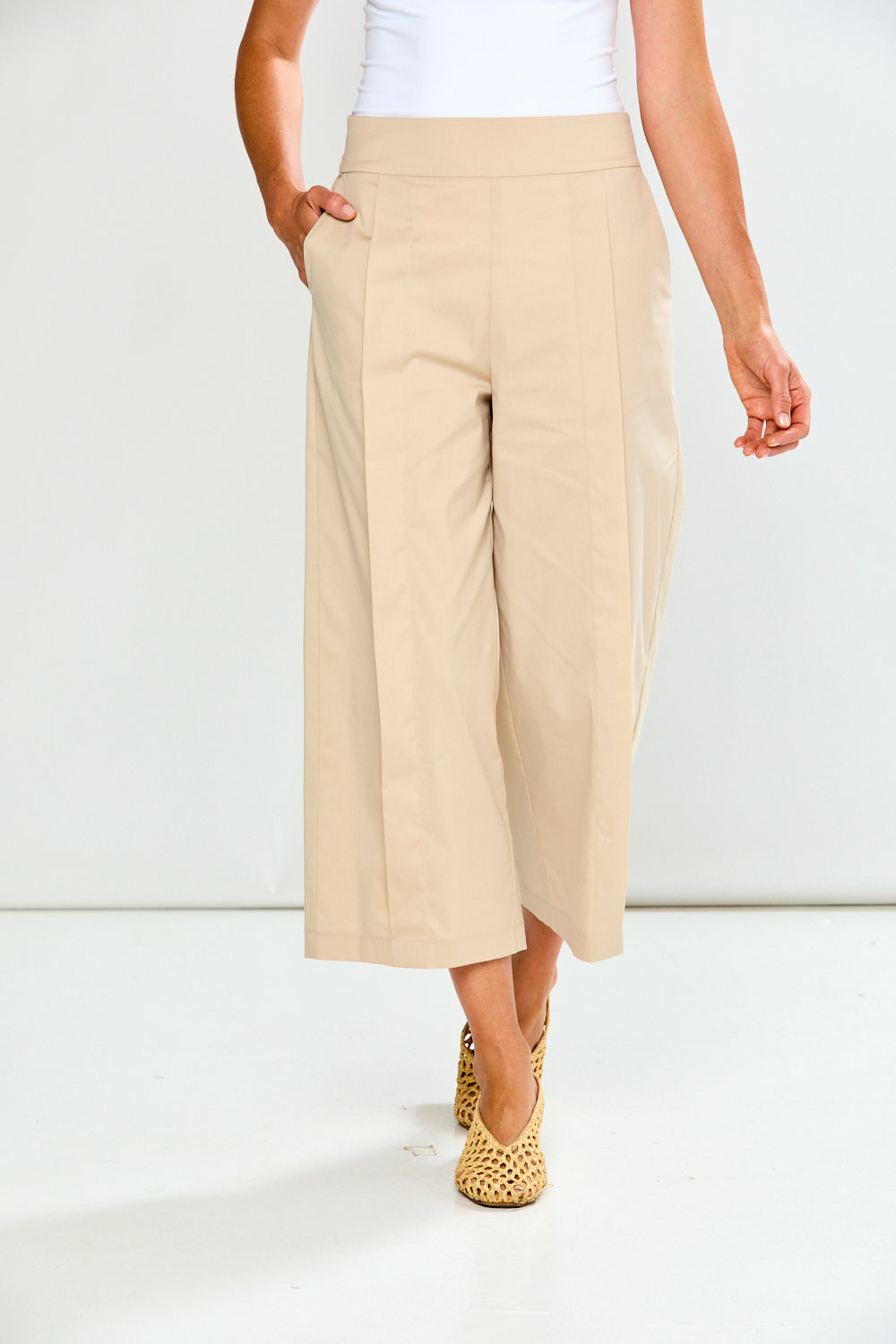 Woman wearing sand wide-leg pants on a white background
