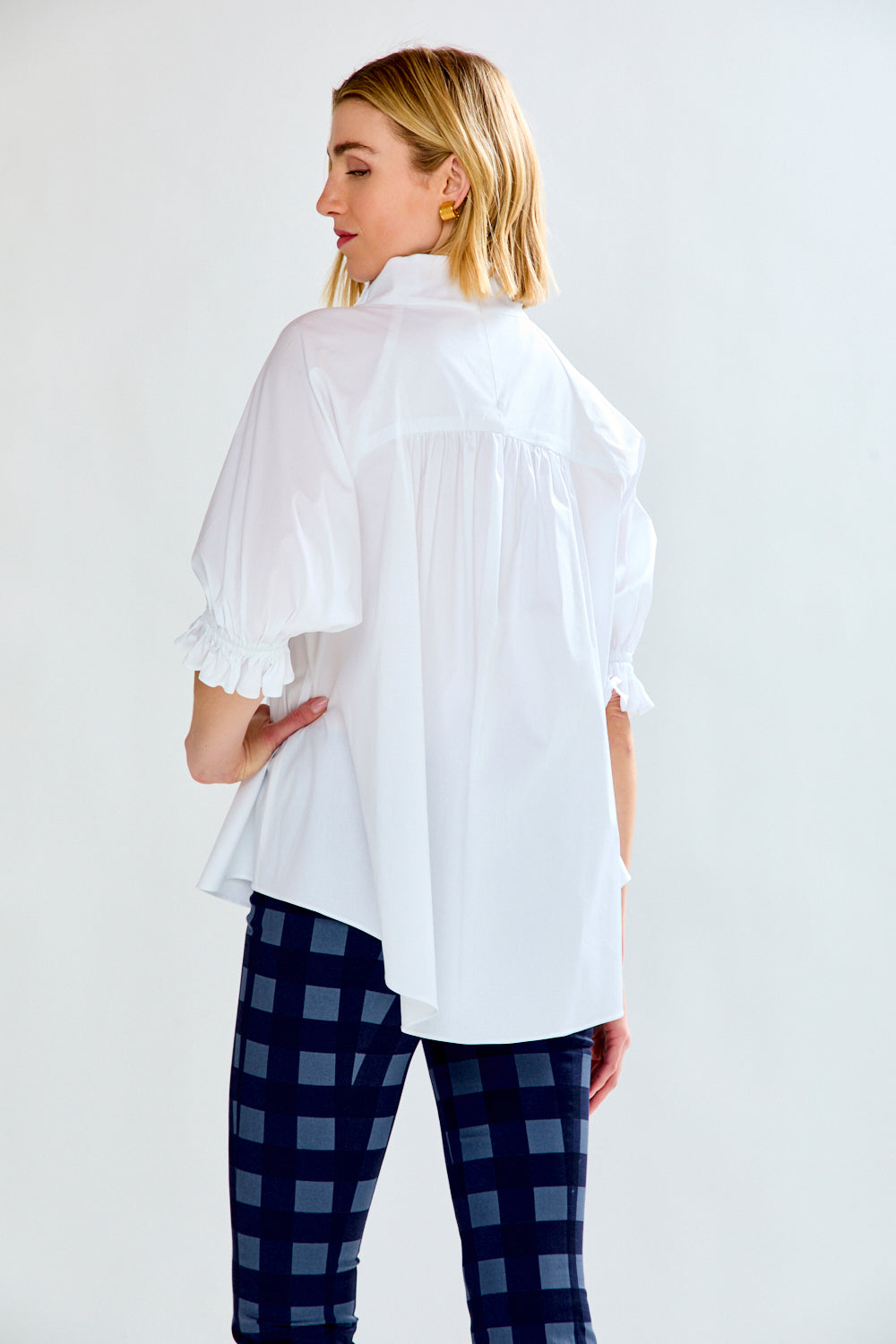 Woman wearing a white blouse and blue checkered pants on a white background