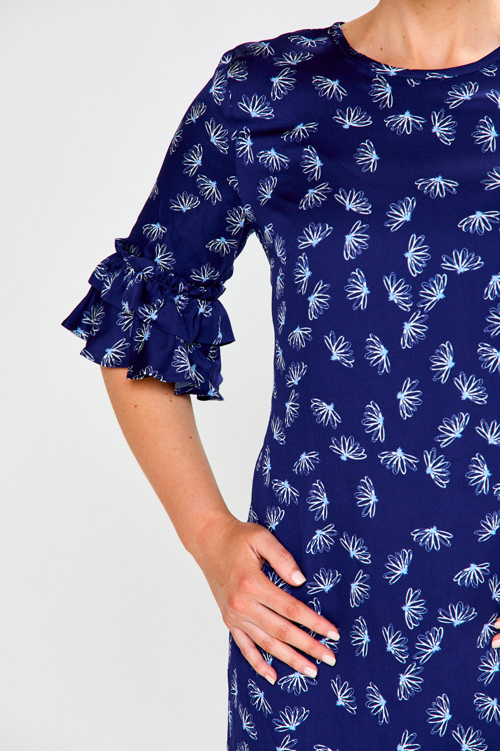 Woman wearing a blue dress with white floral pattern on a white background