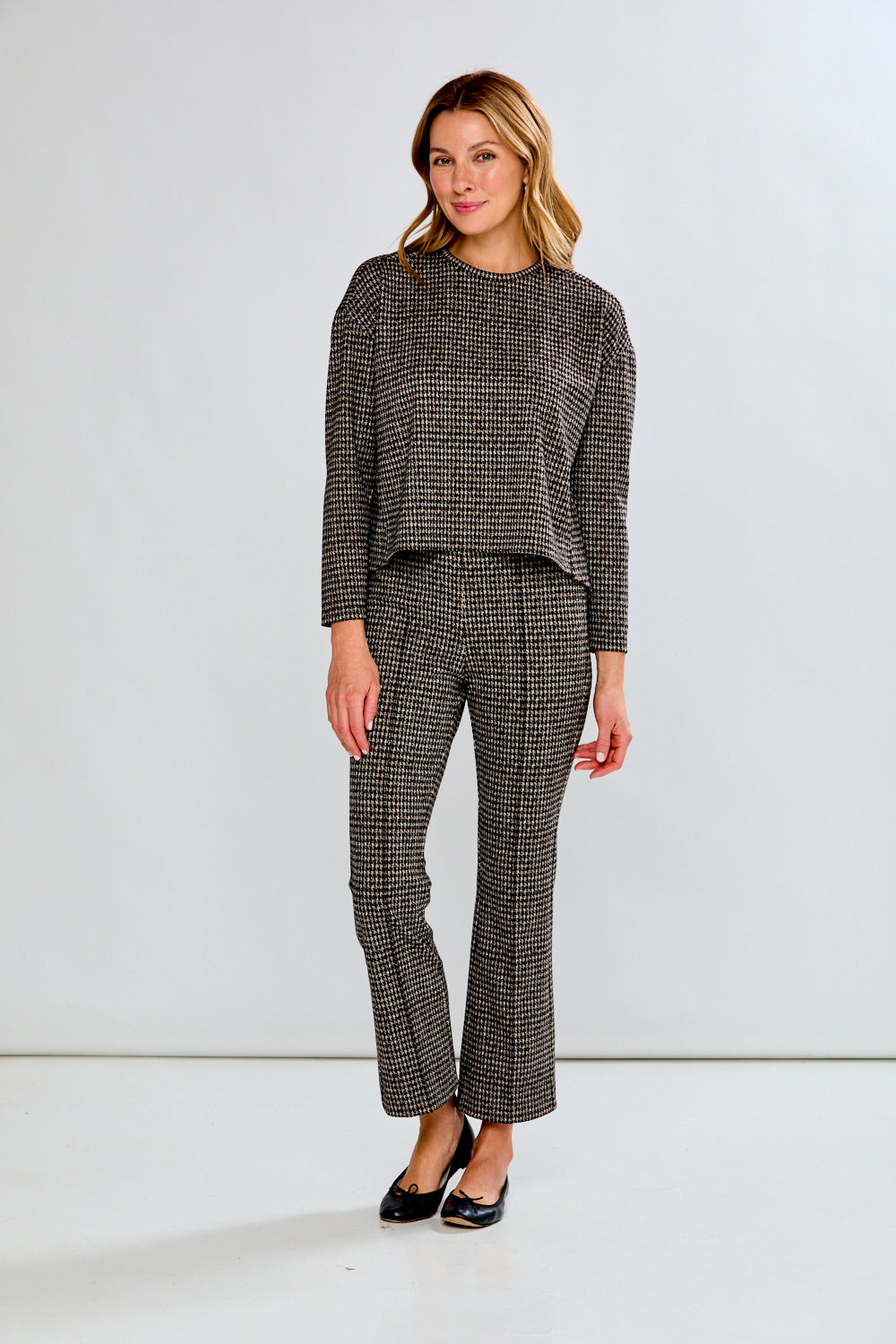 Person wearing houndstooth patterned pants on a plain background
