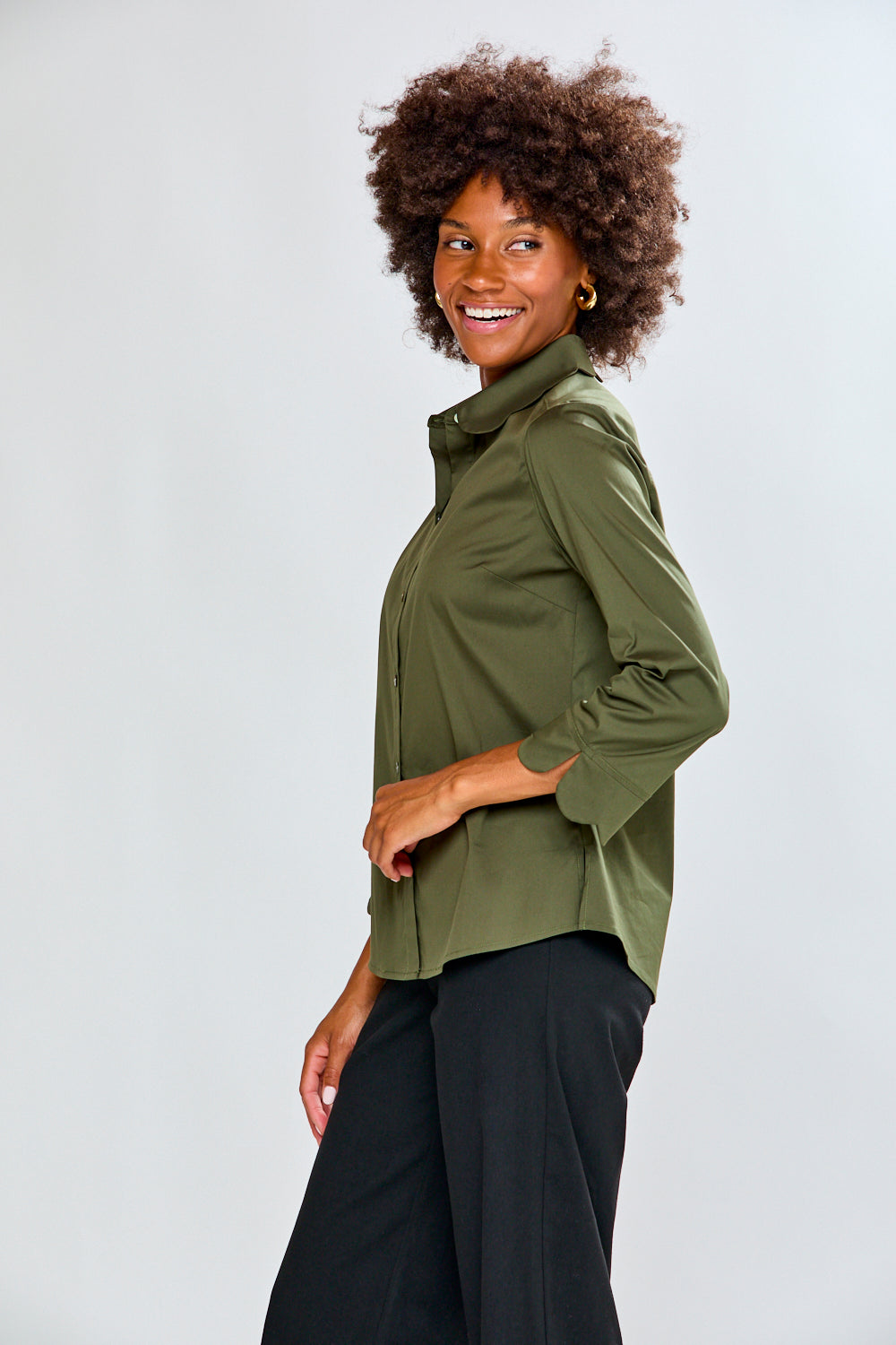 Woman wearing an olive green shirt and black pants on a white background