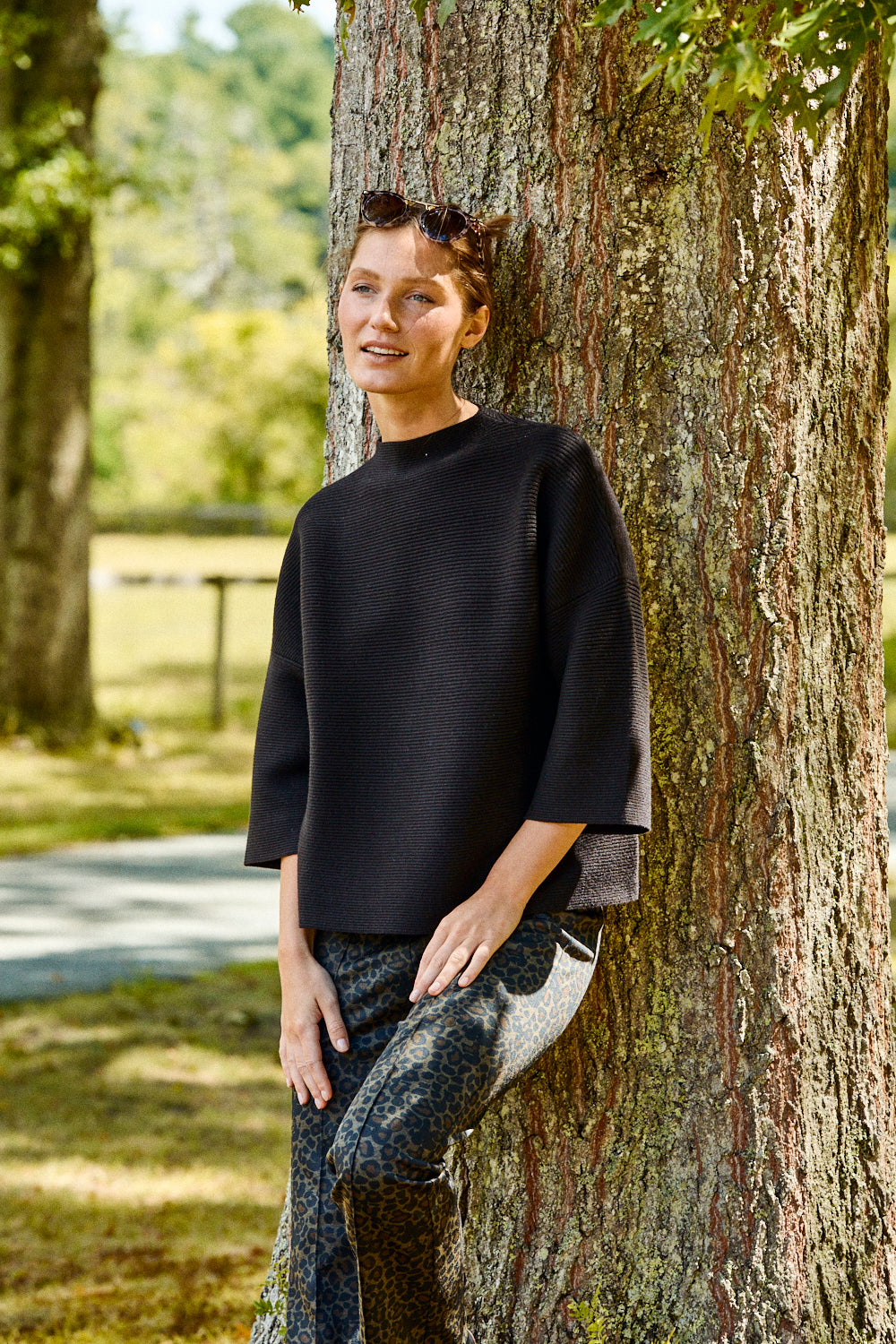 Person leaning against a tree in a park-like setting
