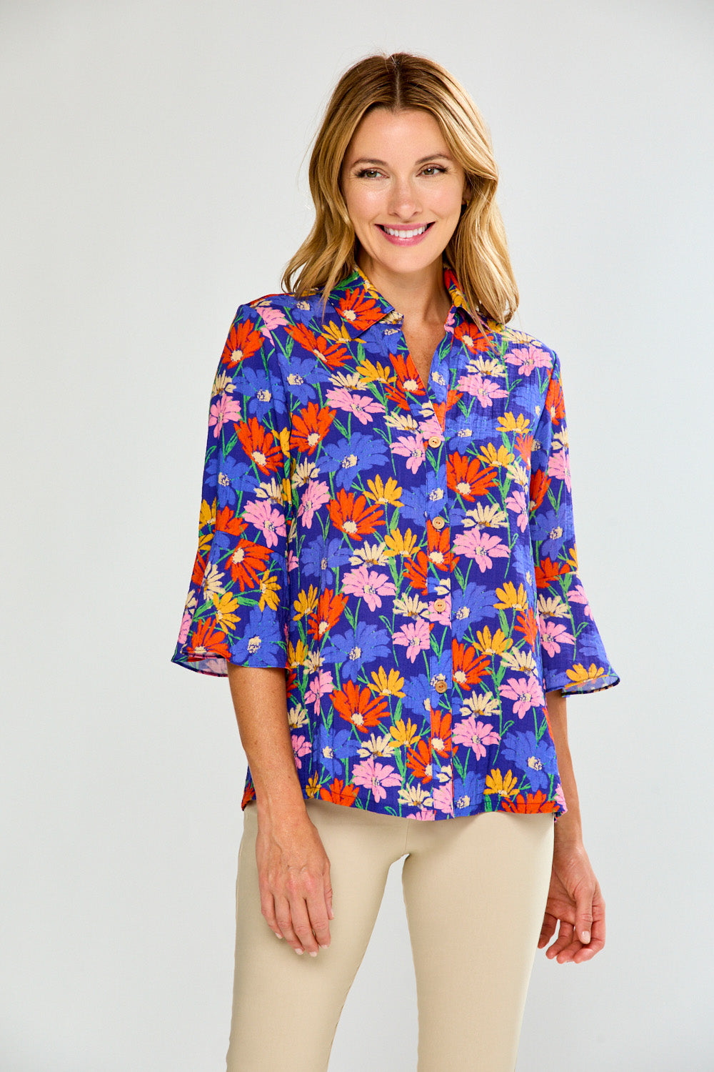 Woman wearing a colorful floral blouse against a plain background